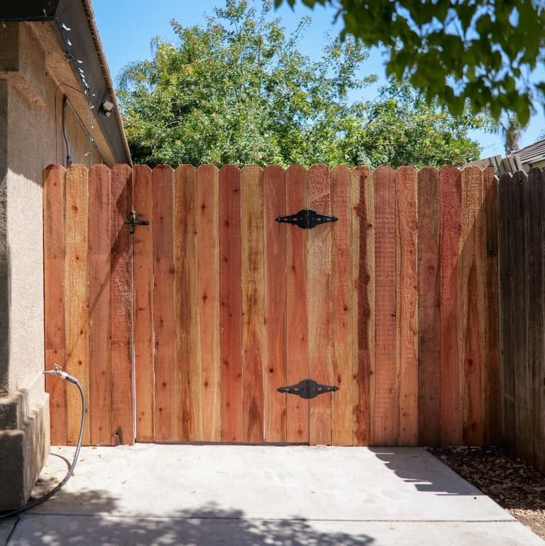 Full-height redwood side-yard gate with black hinge and latch hardware