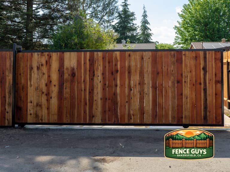 Front view of a wood-infill metal sliding driveway gate on a ground track