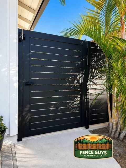 Modern black metal pedestrian gate with palm landscaping