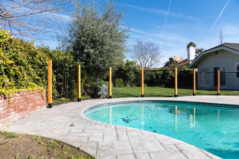 Long hog panel fence run with wood posts around a backyard pool