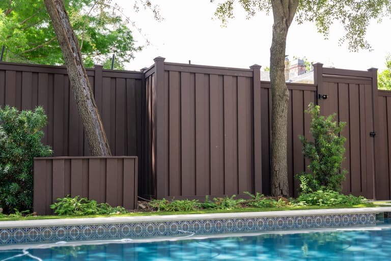 Brown Trex composite privacy fence with gate near a pool