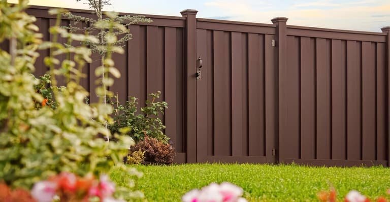Trex composite fence with walk gate in a landscaped yard
